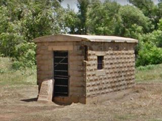 single room jail in stone with iron bars on the door
