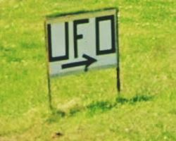 UFO sign and arrow pointing, on the grass by US66
