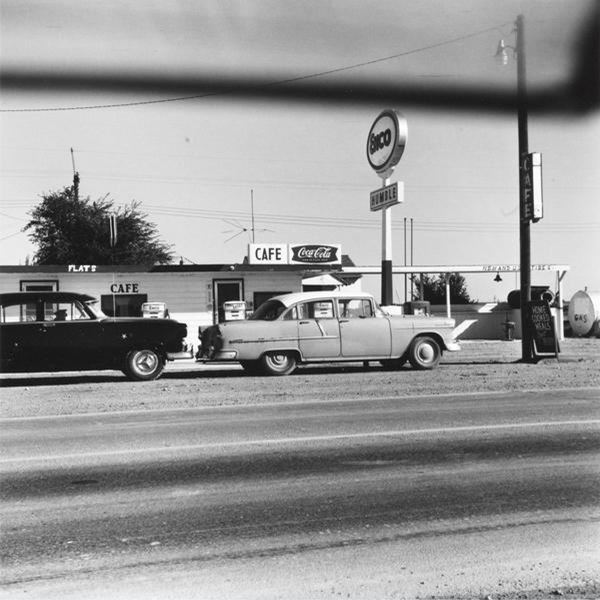 two 1950s cars by cafe and Old gas station black and white photo