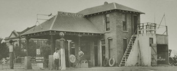 old station, two men, gas pumps and court building in a black and white photo