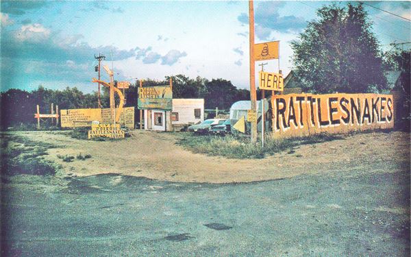 1970 cars, old building and large yellow "Rattlesnakes" sign in color picture 1970s